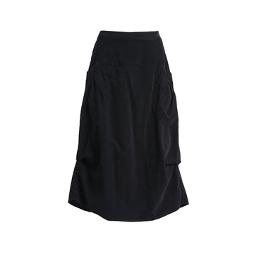 A black skirt in a fine cord fabric with side pockets and side tucks.