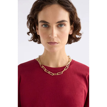 Gold chunky chain necklace on a light grey background.