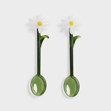 Two green spoons with daisy flower ends on a white background.