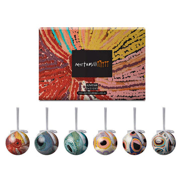 A set of six Christmas baubles each featuring different artwork from Martumili artists. The box lid is pictured too.
