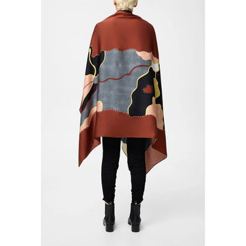 A model is holding out a silk scarf printed with artwork in shades of brown.