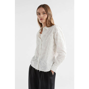 An image of a long sleeved white shirt with feather embroidery. 