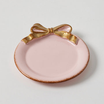 A pink plate with a gold edge and a large gold bow at the top.