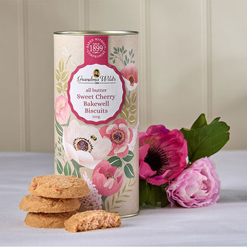 Biscuit tin with floral design and cookies on a light surface.