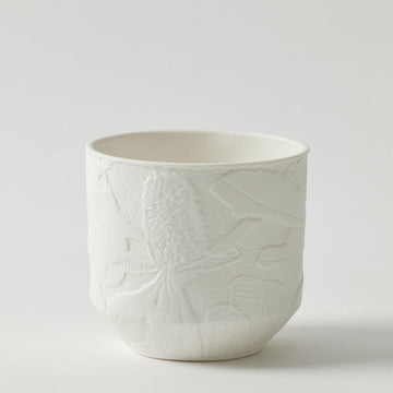 A white porcelain pot planter with an embossed floral design.