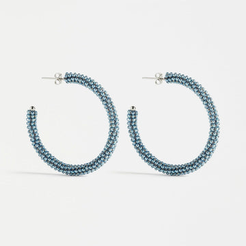 A pair of hoop earrings made up of tiny denim coloured beads.