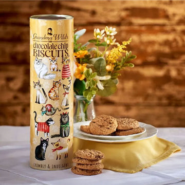 A tube illustrated with cats wearing jumpers next to a plate of chocolate chip cookies.