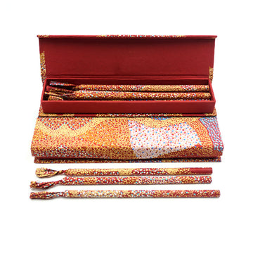 An open box filled with pencils standing on another box. The boxes and pencils are printed with artwork by Lynette Brown.