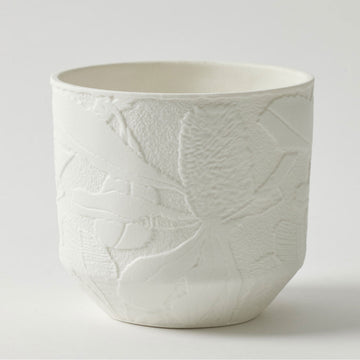 A white pot planter with embossed flowers around the edge.
