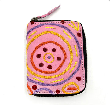 A zippered purse in pink embroidered with artwork by Cedric Varcoe.