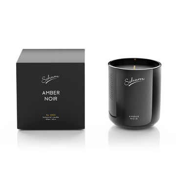 A black glass candle next to a matching black cube box with the text 'Amber Noir' on the front.