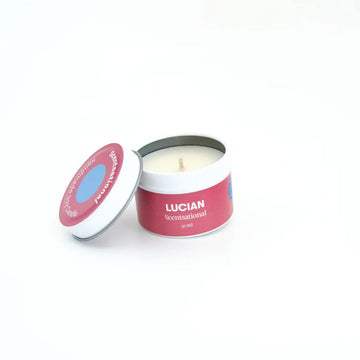 A small candle in a tin with a red pink label and the text 'Lucian Scentsational' around the side.