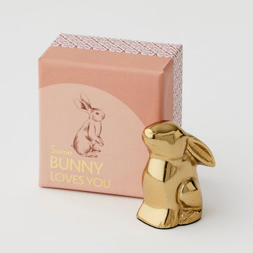 A gold statue of a bunny next to a pink box with the text 'Some Bunny Loves You' on the box.