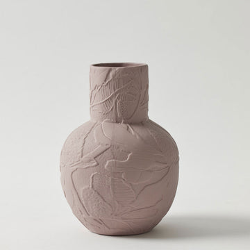 A porcelain vase in a dusty pink colour with a round base and cylinder top and embossed with flowers.