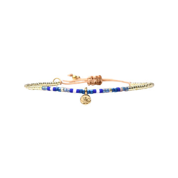 Bracelet with blue beads and a gold charm on a white background.