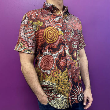 Person wearing a colorful patterned shirt against a purple background.