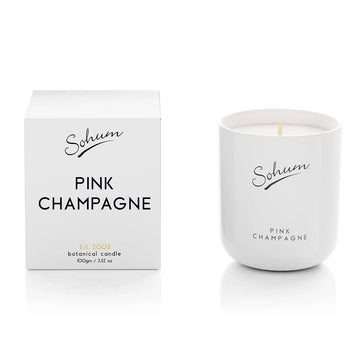 A white glass candle next to a matching white cube box with the text 'Pink Champagne' on the front.