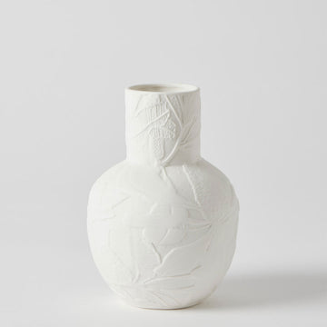 A porcelain vase in white with a round base and cylinder top embossed with flowers.