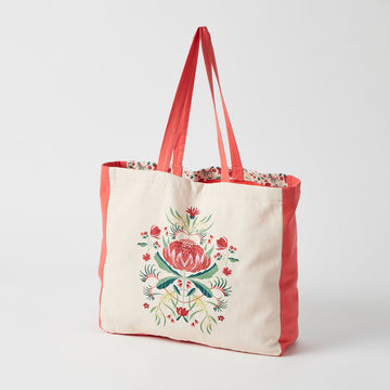 Front view of a tote bag with red sides and straps and an illustration of a waratah flower on the front.