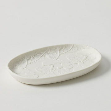 An oval shaped trinket tray embossed with flowers on the inside.