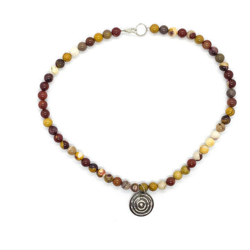 A beaded necklace made from Mookaite with a silver round pendant in the middle.