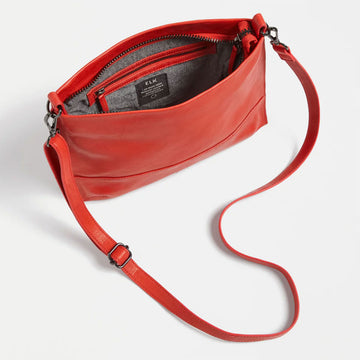 Red leather handbag with a strap on a light gray background.