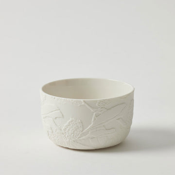 A porcelain white bowl with flowers embossed on the outside.