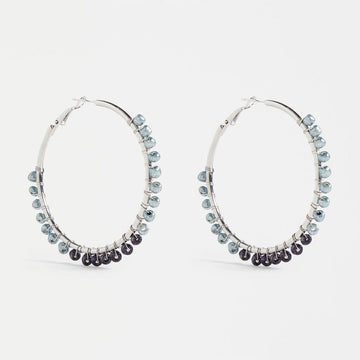 A pair of silver hoop earrings with blue beads around the edges.