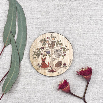 Wooden coaster with animal illustrations on a textured surface with leaves and flowers.