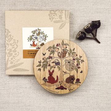 Wooden round trivet board with animal illustrations and packaging on a textured surface