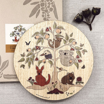 Wooden round trivet with Australian animals and nature design on a textured surface.