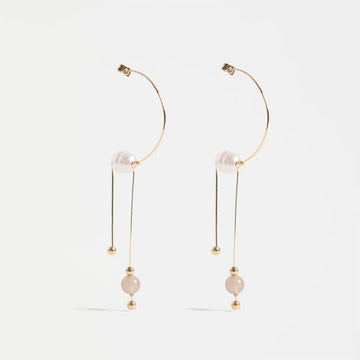 Gold hoop earrings with pearl drops on a white background.