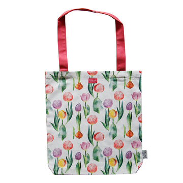 A white tote bag printed with watercolour coloured tulips and a red strap.