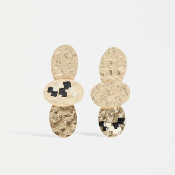 A pair of drop earrings in gold with three oval shapes layered together with a few black marks.