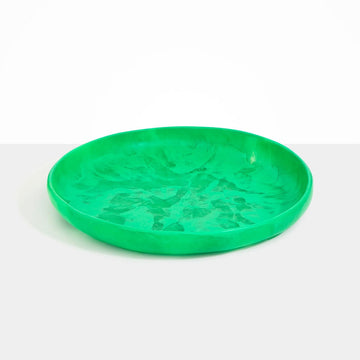 A large round shallow bowl platter made from resin in green.