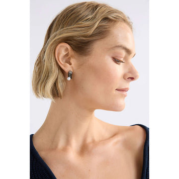 Pair of silver earrings with white pearls on a light grey background.