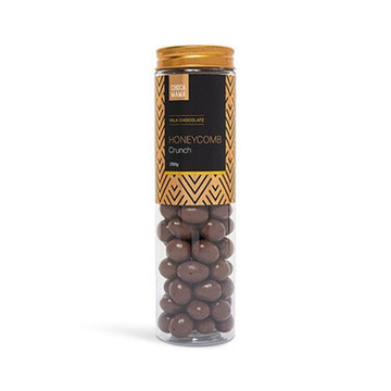 Glass tube filled with chocolate-covered honeycomb on a white background.