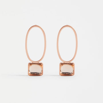 A pair of drop earrings with a hollow oval shaped and a rectangle gem at the bottom, all in the same champagne colour.