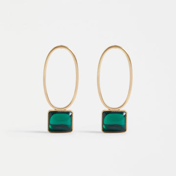 A pair of drop earrings with a hollow oval shaped and a rectangle gem at the bottom, in gold and emerald.