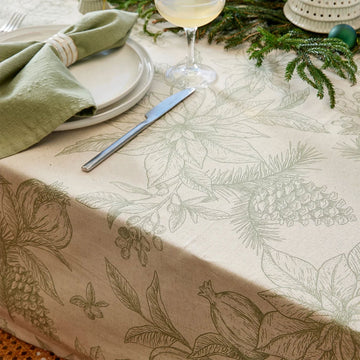 Floral patterned tablecloth with green leaves and berries on a beige background.