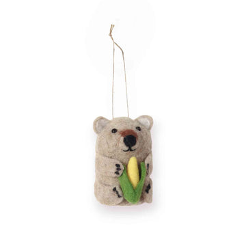 Felted wombat ornament holding a corn cob on a white background