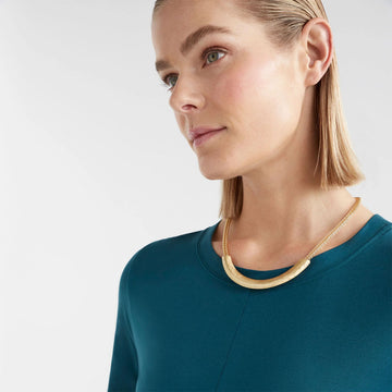 A gold necklace with a round chain and a long gold covering.