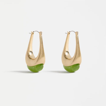Gold hoop earrings with green accents on a light grey background.