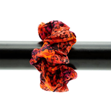 A scrunchie printed with orange and black artwork attached to a black pole.