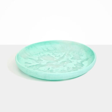 A large round shallow bowl made from mint green resin.