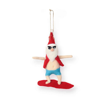 Decorative ornament of a Santa wearing sunglasses, red shirt, blue shorts, riding a  red surfboard on a white background.