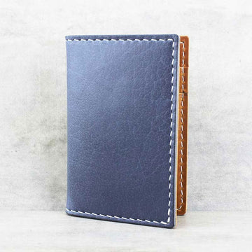 Blue leather cardholder with brown accents on a light gray background.