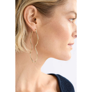 Gold wavy hoop earrings on a light gray background.