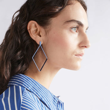 A pair of drop earrings with a hollow diamond shape in ice blue with dark blue thread wrapped around one side.