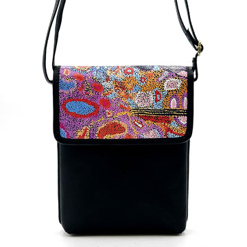 Front view of a leather sling bag in black printed with colourful artwork by Andrea Adamson on the flap.